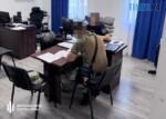 за столом сидять детектив ДБР та військовослужбовець з Житомирщини, який торгував зброєю