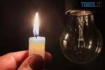 рука тримає палаючу свічку біля лампочки, яка не світить